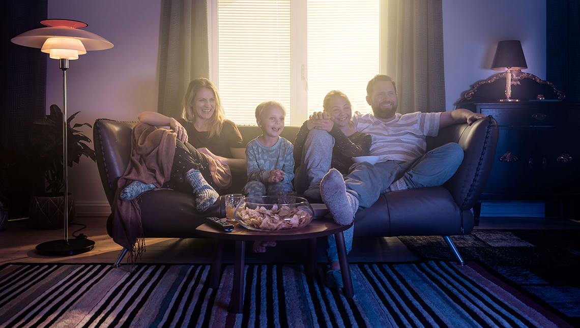En familie på fire sitter i en sofa og ser på TV